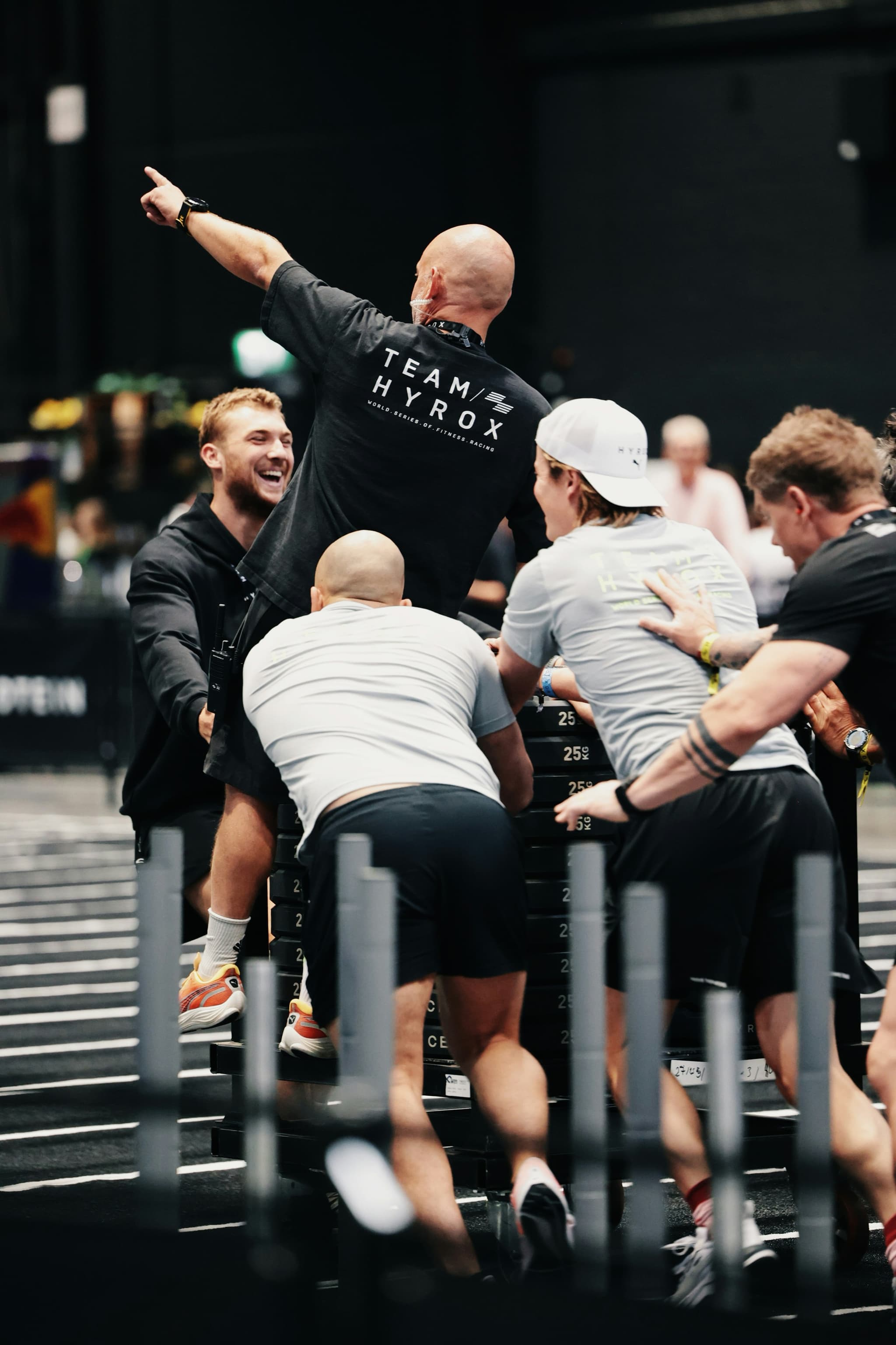 Trainer feiert mit Athleten Fitness-Trainer mit erhobener Hand feiert neben Athleten bei einem Indoor-Gym-Wettbewerb.